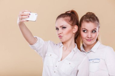 Eğlenceli bağ selfie kavramı. Kız kardeşler veya arkadaşlarım, akıllı telefon kamera ile kendini fotoğrafta iki öğrenci sarışın kız komik eğlenceli, pozitif duygu yüzünde sahip