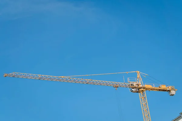Construction site building hoisting crane on evening clear blue sky background. Industrial object concept.