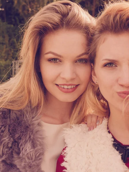 Sıcak sonbahar havasında şık kıyafetler giyen iki şık kadın boş zamanlarını dışarıda geçiriyorlar.