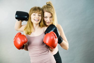 Arkadaşlık, insan ilişkileri kavramı. Mutluluktan gülümseyen iki mutlu bayan arkadaş boks eldivenleri giyip spor yapıyorlar..