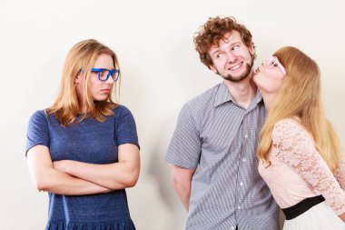 Kıskançlık ve ihanet kavramı. Terk edilmiş denizanası mutlu çifti izliyor. Genç ve çekici sarışın kadın yakışıklı oğlanı öpüyor..