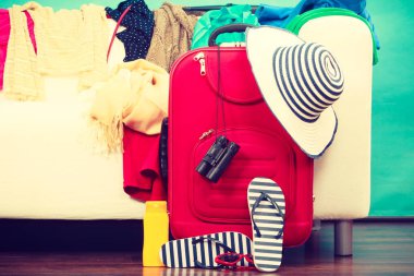 Seyahat, gezi kavramı önce delilik için ambalaj. Kırmızı çanta ile flip flop, Güneş şapka ve dürbün üzerinde. Divan arka planda karışıklık