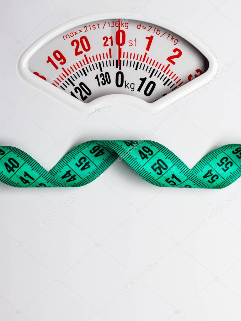 Dieting weightloss slim down concept. Closeup measuring tape on white weight scale copy space text area