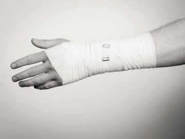 Kırık ve çıkık bir kavram. Beyaz bandaj erkek elinde. Genç adam acı palm kol için yararlı ilaç.