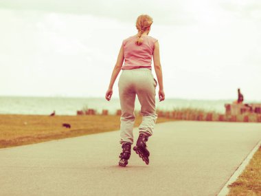 Tatil, aktif yaşam tarzı özgürlük kavramı. Genç kadın üzerinde paten açık havada deniz kenarı, kız paten güneşli sürme yerleştirmek