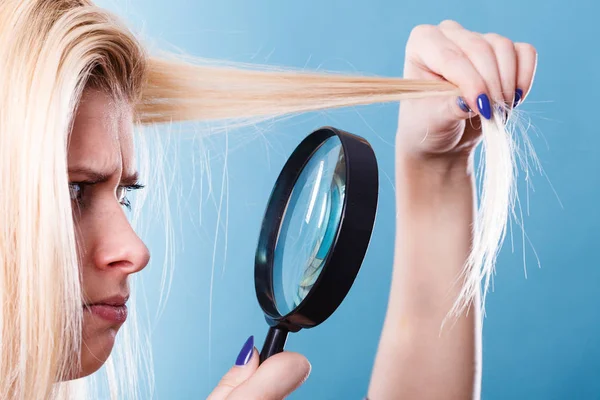 ヘアケア ヘアスタイ リング コンセプトを漂白剤の悪い影響 ブロンドの女性は彼女の破損 分割の髪を見て虫眼鏡を通して終了します — ストック写真
