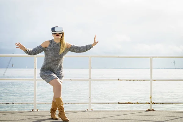 Young woman testing VR glasses outside. Female wearing virtual reality headset during spring weather,