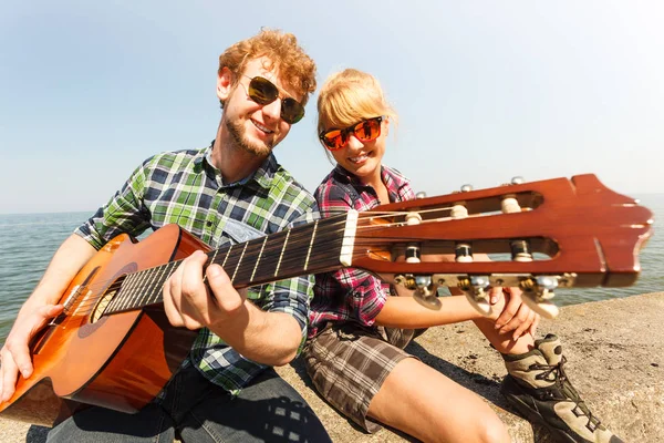 Jovem Hipster Feliz Tocando Guitarra Para Mulher Por Mar Oceano — Fotografia de Stock