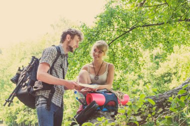 Turist ve erkek turistler dinlenirken harita okuyorlar. Yol gösterici arayan genç çiftler. Yaz tatili seyahati.