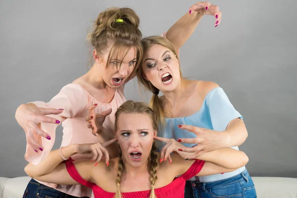 Woman being bullied by her two female friends. Women having argument. Angry fury girls screaming at her friend or younger sister. Friendship difficulties, rivaly and envy problems.