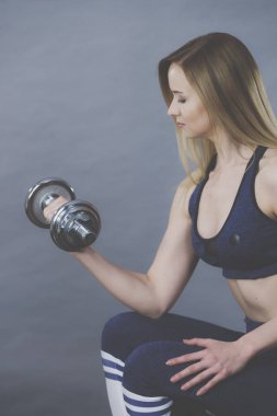Güçlü kadın dumbell ağırlık kaldırma. Bina kas kazanma çekici sarışın model kız egzersiz uygun. Fitness ve vücut geliştirme, Grey