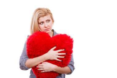 Sevgililer günü, romantizm ve ilişki sembolleri kavramı. Büyük kırmızı yastık kalp şeklinde tutan Uhhappy üzgün genç kadın