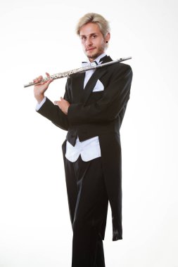 Klasik müzik eğitimi konsepti. Erkek flütçü müzisyen flüt çalıyor. Paltolu genç adam enstrüman tutuyor.