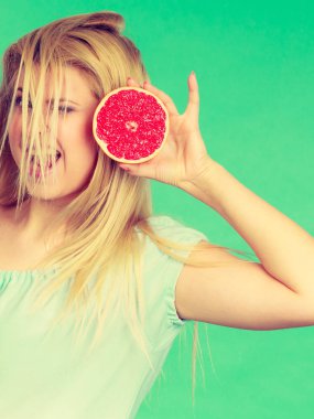Sağlıklı beslenme, vitamin dolu ferahlatıcı yiyecekler. Tatlı narenciye meyvesi tutan mutlu çılgın kadın, rüzgarlı saçları olan kırmızı greyfurt..