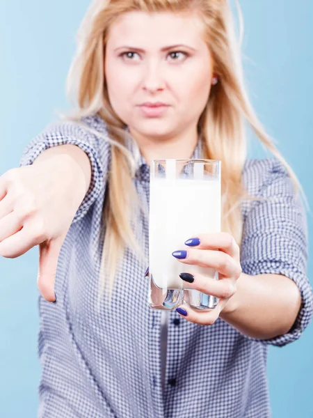 Lactose intolerance, health problem with dairy food products concept. Woman holding glass of milk showing thumb down gesture.