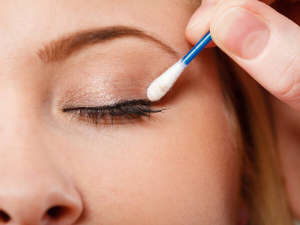 Visage, beauty concept. Closeup portrait of woman face getting her eye makeup done with cotton buds