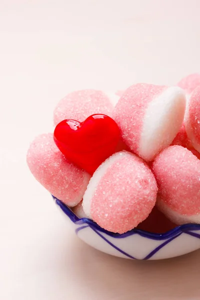 甘い食べ物お菓子 ピンクのゼリーまたは赤いハートの愛のシンボルで飾られた木製のテーブルの上のボウルに砂糖とマシュマロ — ストック写真