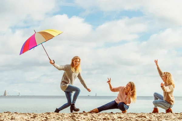 Birlikte harika vakit geçiren üç kadın. Renkli bir şemsiye tutan bir kadın.