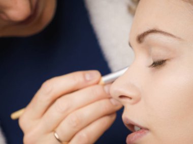 Model, genç ve güzel bir kadın, göz farı sürerek, profesyonel bir sanatçı tarafından makyaj yaptırıyor..