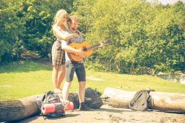 Macera, turizm, yaz tatilinin tadını çıkarmak. Genç bir çift kampta gitar çalarken eğleniyor.