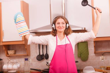 Yemek hazırlama ve gıda kavramı yapma. Pembe önlük giyen ve mutfakta ayakta kulaklık müzik dinleme Modern güzellik kadın ev kadını aşçı Şef.