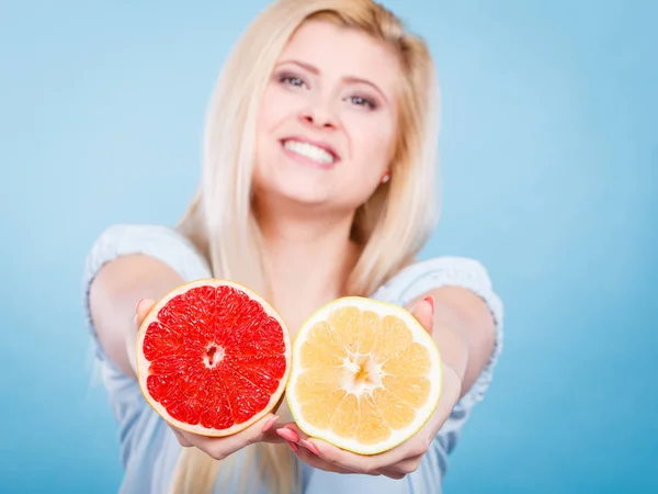女人握在手 在蓝色的两半的柚子红色和黄色的柑橘类水果的小女孩微笑着 健康的食物 饮食概念 — 图库照片