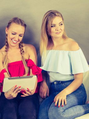 Eğleniyor koltukta oturan kadınlar akıllı dijital pc tablet modern cihaz kullanarak internette sörf