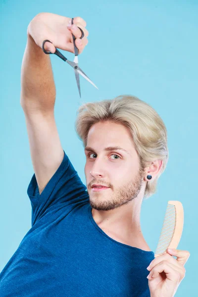风格和时尚 年轻时髦的男性发型师理发师 带着换新造型的想法 带着剪刀和木制梳子的金发男人 蓝色的发型 — 图库照片