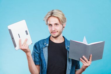 EBook okuyucu ve kitap tutan erkek öğrenci. Modern eğitim teknolojisi ve geleneksel yol yöntemi arasında seçim. Dijital tablet pc ve ders kitabı ile genç adam.