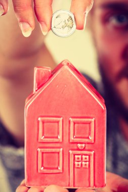 Ev tasarruf ve finans, ekonomi kavramı. Kumbara house, stüdyo ışık arka plan üzerinde atış şeklinde para madeni para koyarak adam