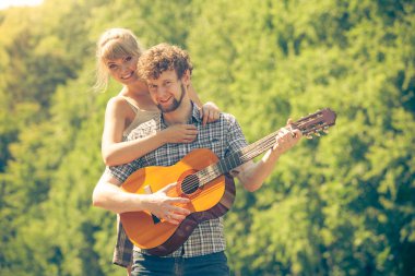 Macera, turizm, yaz tatilinin tadını çıkarmak. Genç bir çift kampta gitar çalarken eğleniyor.