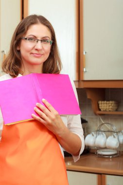 Olgun ev kadını yemek kitabı için tarifi arıyorum elinde Şef mutlu. Orta yaşlı kadın mutfakta yiyecek hazırlama.