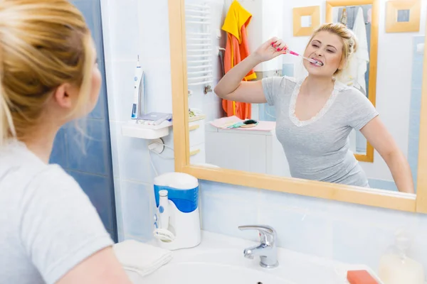 女人刷清洁牙齿特写 用牙刷在浴室 看着镜子的金发女郎 口腔卫生 — 图库照片