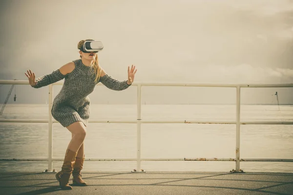 Young woman testing VR glasses outside. Female wearing virtual reality headset during spring weather,