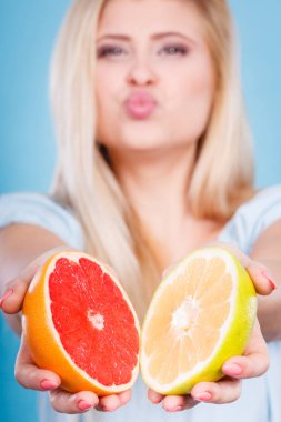 Kadın gülümseyen kız iki halfs greyfurt, ellerinde mavi kırmızı ve sarı narenciye meyve tutan. Sağlıklı gıda, diyet kavramı.