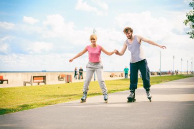 Aktif genç insanlar arkadaş eğitim paten açık uygun. Kadın ve erkek çift zevk spor sürme elele.