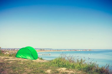 Turizm ve Rekreasyon. Çayır su deniz göl tarafından çevrili doğal alanda küçük yeşil çadır.