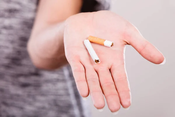 Closeup of broken cigarette on male hand. Winning with addicted nicotine problems, stop smoking. Quitting from addiction concept.