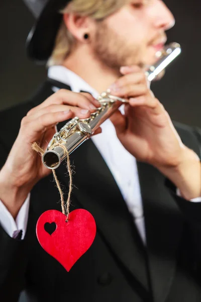 バレンタインデー愛のメロディーのコンセプトです フルート音楽のフルート奏者の男性音楽家の実行者 楽器と赤のハートとエレガントなスタイリッシュな若者 — ストック写真