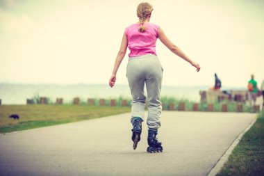 Tatil, aktif yaşam tarzı özgürlük kavramı. Genç kadın üzerinde paten açık havada deniz kenarı, kız paten güneşli sürme yerleştirmek