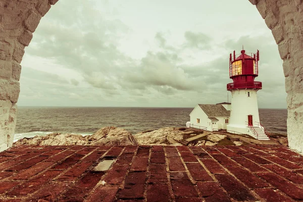 Kayalık deniz Sahili, Güney Norveç, Lindesnes Fyr feneri kenarında tarihi kırmızı beyaz deniz feneri