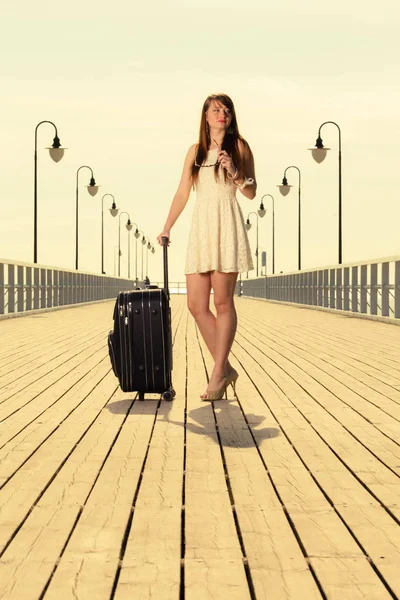 パッキング 旅のコンセプト バック グラウンドで彼女のスーツケースを考えて冒険 桟橋の横に立ってをホワイト ショート ドレスを着ている女性 — ストック写真