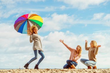 Birlikte harika vakit geçiren üç kadın. Renkli bir şemsiye tutan bir kadın.