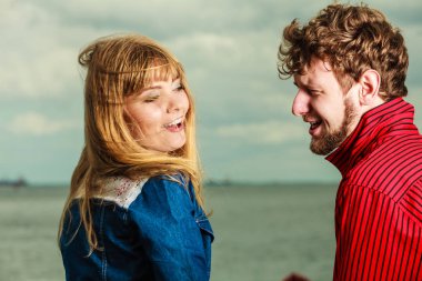 Sevgi dolu genç bir çift kumsalda birlikte vakit geçiriyorlar. Denize yakın oturuyorlar.