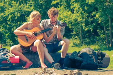 Macera, turizm, yaz tatilinin tadını çıkarmak. Genç bir çift kampta gitar çalarken eğleniyor.
