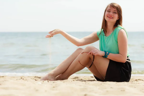 休暇の概念 背景に海とビーチの上に座って短いのカラフルなドレスを着て幸せな笑顔の女性 — ストック写真