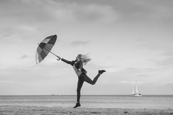 偉大な概念を感じて秋寒さを楽しんでいます 晴れた日 黒と白の近くのビーチのカラフルな傘とジャンプ女性 — ストック写真
