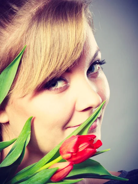 People and nature. Young woman with tulip on her face live in peace with floral world. Girl feel connection to natural environment.