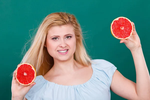 Kadın gülümseyen kız kırmızı greyfurt iki halfs narenciye meyve ellerinde yeşil holding. Sağlıklı bir diyet yemek. Yaz tatil kavramı eğlenceli.