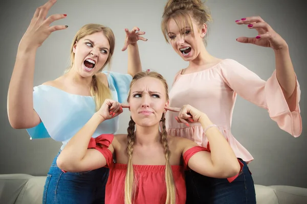 Woman being bullied by her two female friends. Women having argument. Angry fury girls screaming at her friend or younger sister. Friendship difficulties, rivaly and envy problems.